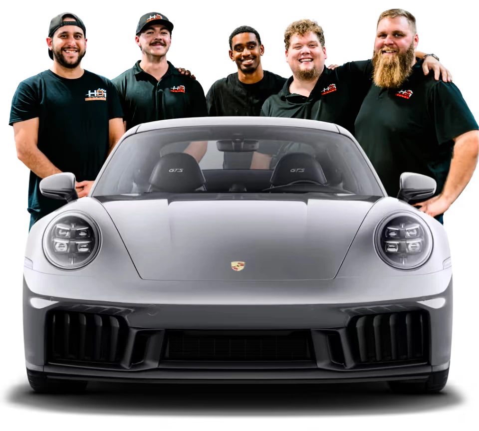 The HBI Auto team standing behind a silver Porsche 911 GTS